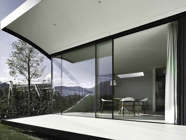 Frameless glass corner opening a dining room to the garden